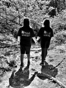 Two members of Nordic Walking Watford wearing Hertfordshire Mind Network t-shirts holding hands. 
