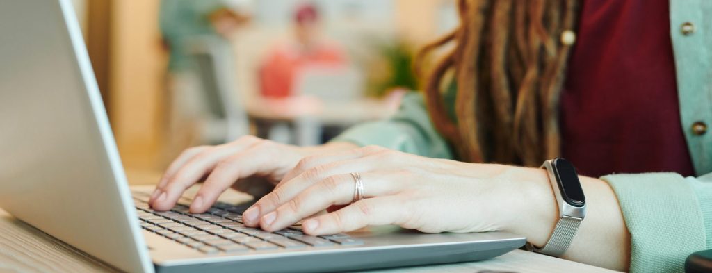 A young woman with dreadlocks, typing on her laptop.