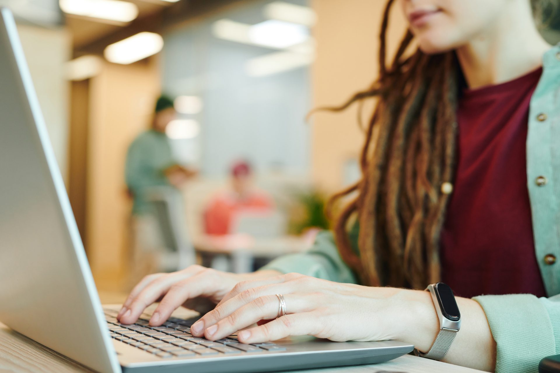 A young woman with dreadlocks, typing on her laptop.