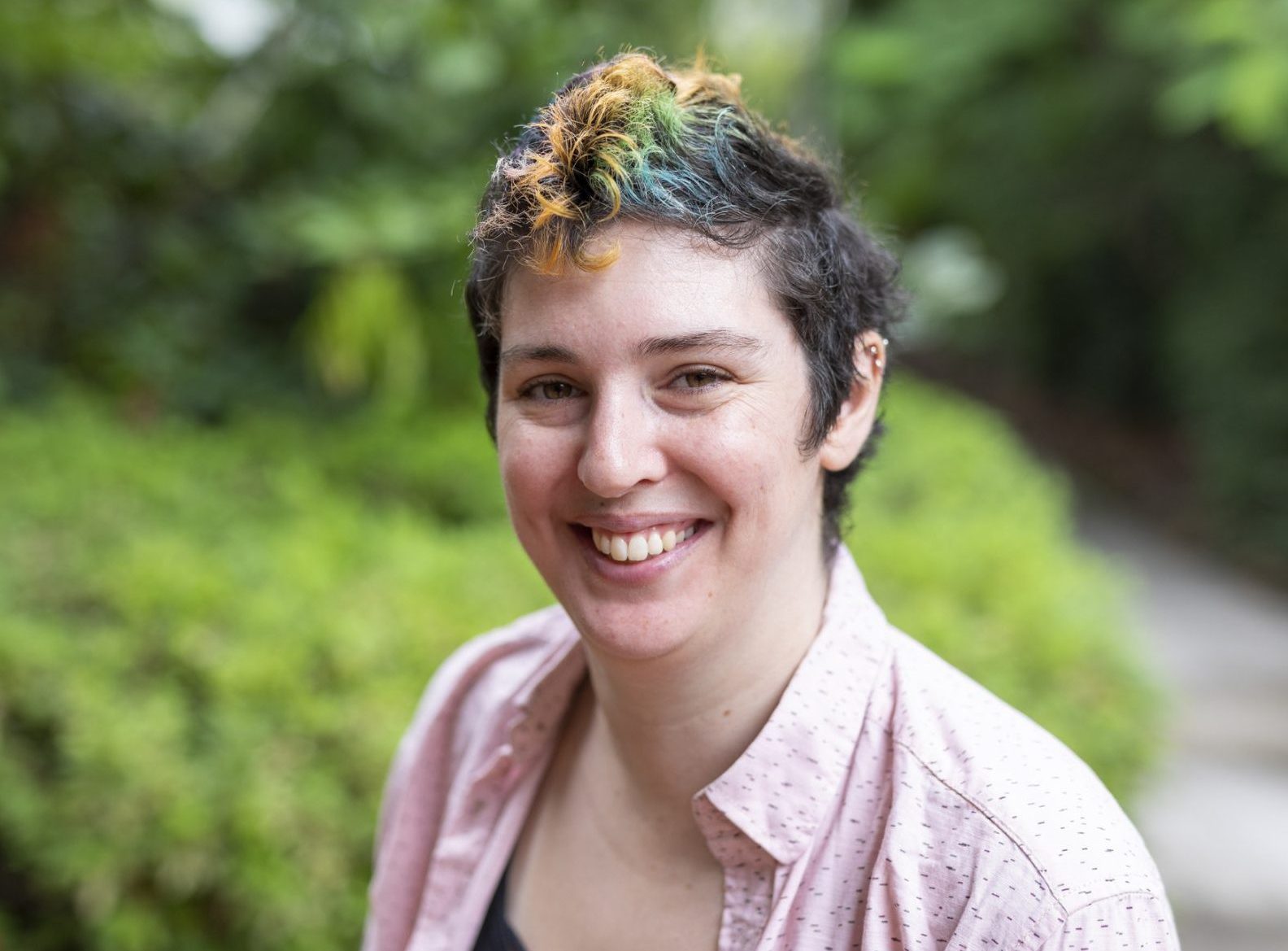 a women with short dark hair is smiling broadly at the camera.