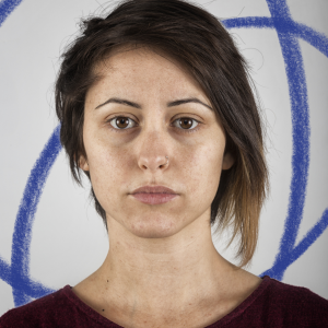 a women with dark, shoulder length hair is looking at the camera with a neutral expression