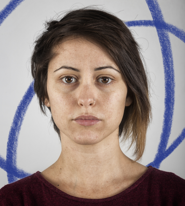 a women with dark, shoulder length hair is looking at the camera with a neutral expression
