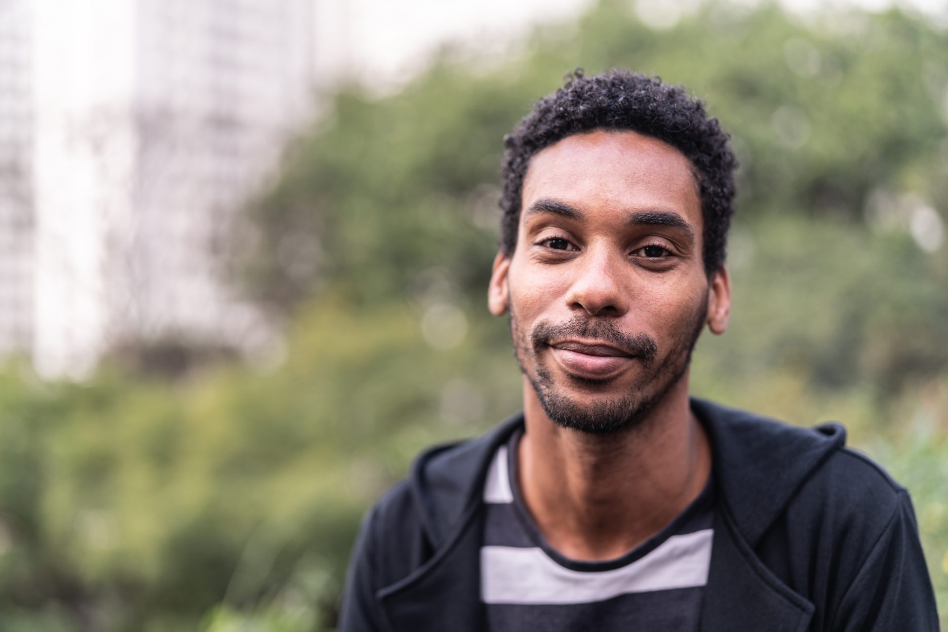 A young man outside, smiling at the camera