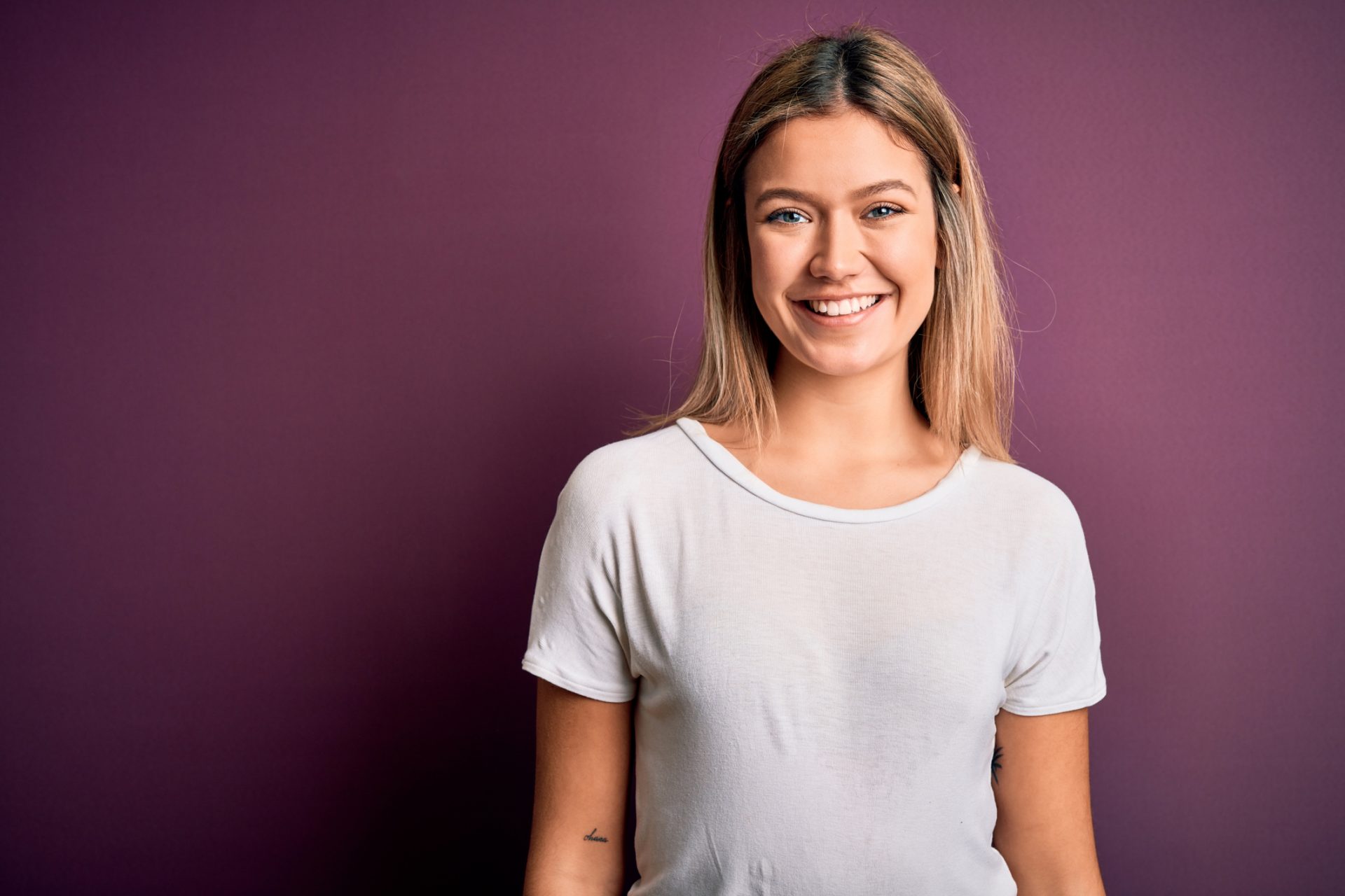 a girl with blue eyes and long blond hair is standing inside and smiling at the camera