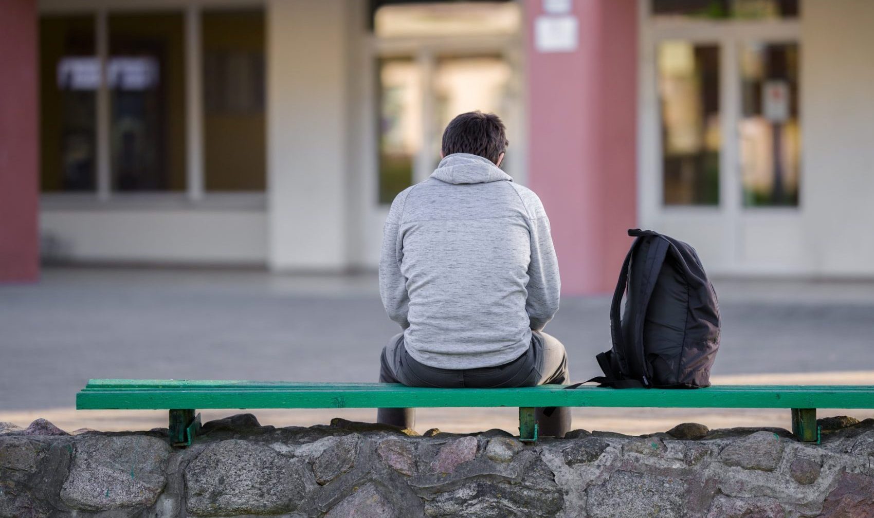 The back of a man sat on a bench outside